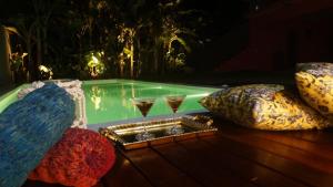 a swimming pool with two glasses of wine at Castelo Pink Boutique Hotel in Uruau