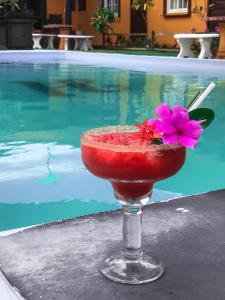 a drink in a glass with a flower in it next to a pool at Big Daddy's Beach Club & Hotel in Puerto Armuelles
