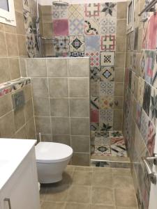 uma casa de banho com WC e azulejos na parede em Villa Lithos Parga em Parga