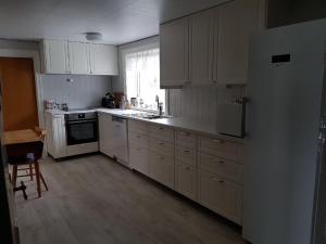 eine Küche mit weißen Schränken und einem Kühlschrank in der Unterkunft Presthus Gård in Ølve
