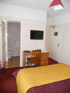 a bedroom with a bed and a desk and a television at Gateway Lodge in Speke