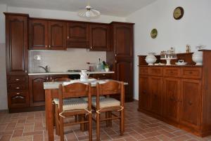 uma cozinha com armários de madeira e uma mesa e cadeiras em Babbo Rino em Vagliagli
