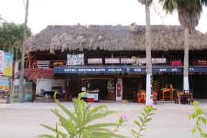 un edificio con techo de paja con mesas y sillas en Hotel LOL-HA, en Cobá