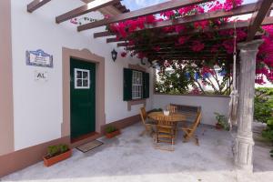 een patio met een tafel en stoelen en roze bloemen bij Casa das Vinhas in Feteira