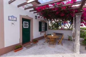 un patio con mesa, sillas y flores rosas en Casa das Vinhas, en Feteira