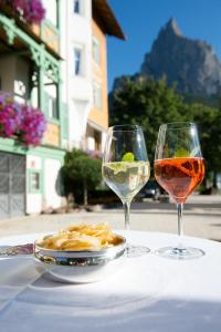 dois copos de vinho e um prato de comida numa mesa em NaturResidence Dolomitenhof em Siusi