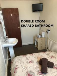 a bedroom with a double room shared bathroom with a bed and a sink at Coco Beach Hotel in Blackpool