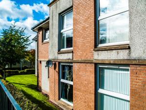 Un edificio de ladrillo con ventanas a los lados. en King Court Apartment, en Motherwell