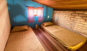 two beds in a room with a brick wall at Villa Justen Pousada in Lençóis