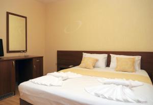 Schlafzimmer mit einem Bett mit weißer Bettwäsche und einem Spiegel in der Unterkunft Къща за гости "ВАИС" in Sandanski