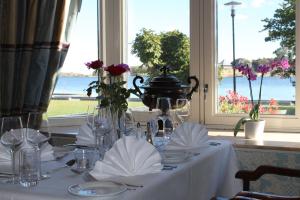 ein Tisch mit weißer Tischdecke und Gläsern und ein Fenster in der Unterkunft Hotel Wassilioff - Unike Hoteller in Stavern