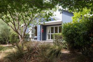 a small blue house with a window and trees at The Claremont Motel in Martinborough