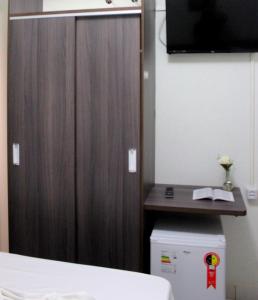 a bedroom with a wooden door and a tv at Luz Hotel in Goiânia