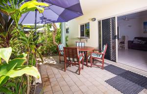 Mission Beach的住宿－使命珊瑚礁度假酒店，庭院配有桌椅和遮阳伞。