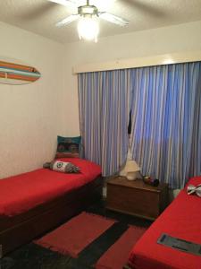 a bedroom with two beds and a window with blue curtains at Villaggio Riviera in Punta del Este