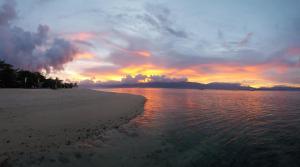 a sunset on the beach with the sun setting at Arena Island Resort in Narra