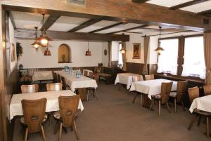 un restaurante con mesas y sillas blancas y ventanas en SchöpPerle en Häusern