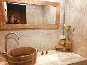 a woman taking a picture of a bathroom with a tub at Baangaimuan in Lamphun