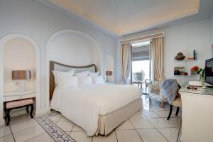 a bedroom with a large white bed and a living room at Capri Tiberio Palace - The Leading Hotels of the World in Capri +37 photos