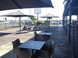 eine Reihe von Tischen und Stühlen mit Sonnenschirmen in der Unterkunft Kooyong Hotel in Mackay