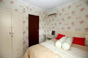 a bedroom with a bed with red and white pillows at Apartemen Mediterania Garden by Netty in Jakarta