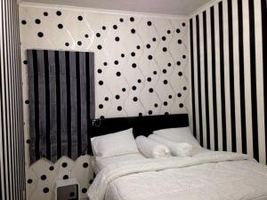 una camera da letto con letto a righe bianche e nere di Apartemen Mediterania Garden by Netty a Giacarta