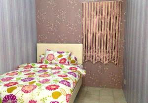 um quarto com uma cama com um edredão floral em Apartemen Mediterania Garden by Netty em Jacarta