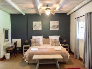 a bedroom with a large bed and a ceiling fan at Franschhoek Country Cottages in Franschhoek
