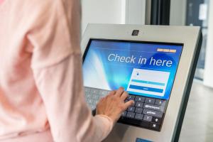 a woman typing on a laptop computer with the words check in here at GreenStar Hotel Joensuu in Joensuu