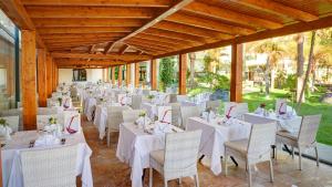 a room with white tables and chairs and trees at Hipotels Natura Palace Adults Only in Playa Blanca