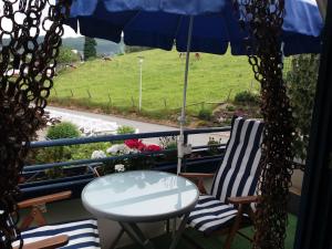a table and two chairs and an umbrella on a balcony at Haus Elsholz Willingen in Willingen