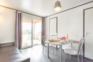 une salle à manger avec une table et des chaises blanches dans l'établissement Village Vacances Le Parc Des Chênes (by Popinns), à La Croix-Valmer