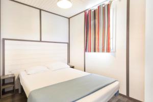 a bedroom with a bed and a painting on the wall at Village Vacances Le Parc Des Chênes (by Popinns) in La Croix-Valmer