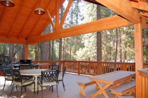 a wooden deck with tables and chairs in the woods at 26 Deer Den in North Wawona
