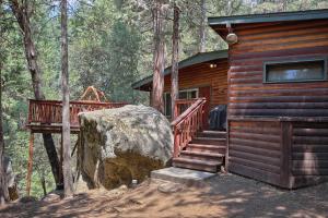 une cabane en rondins avec un escalier et un grand rocher. dans l'établissement 1L The Tree House, à North Wawona