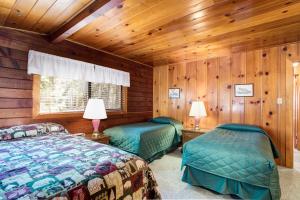 two beds in a room with wooden walls at 55 Deer Creek in Wawona