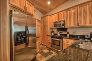 une cuisine avec des armoires en bois et un réfrigérateur en acier inoxydable dans l'établissement 1L The Tree House, à North Wawona