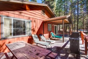 a cabin with a wooden deck with a table and chairs at 9B Deer Hollow in Wawona