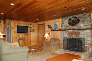 a living room with a stone fireplace and a tv at 26 Deer Den in North Wawona