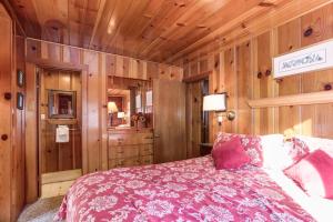 1 dormitorio con paredes de madera y 1 cama con manta rosa en 59 Hansen Cabin, en North Wawona