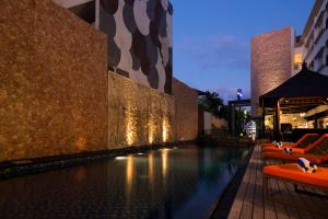 a swimming pool with orange chairs next to a building at Natya Hotel Kuta in Kuta