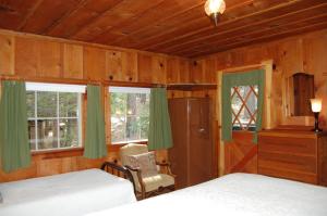 a bedroom with two beds and a chair and two windows at 6S Fretzs Den in South Wawona