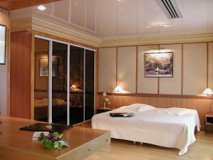 a bedroom with a large white bed and a fireplace at Relais de la Poste in Magescq