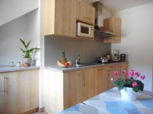 a kitchen with wooden cabinets and a table with flowers at Residence Hofer in Valdaora