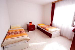 2 łóżka pojedyncze w pokoju z oknem w obiekcie Villa San w mieście Malinska