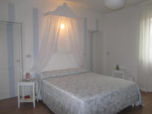 1 dormitorio con 1 cama blanca y 2 mesas en B&B Le Stagioni en Loreto Aprutino