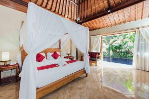 a bedroom with a bed with a mosquito net at Kuta Puri Bungalows, Villas and Resort in Kuta