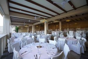 um grande salão de banquetes com mesas e cadeiras brancas em Le Cale D'Otranto Beach Resort em Otranto