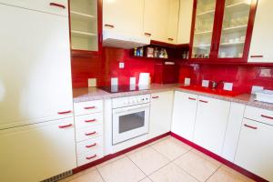 a kitchen with white cabinets and red walls at Apartment Sara in Vitanje