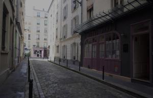 an empty street in a city with buildings at Hotel Anya in Paris